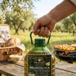 Hand trägt Muvax Oliventresteröl-Kanister am Henkel, im Hintergrund Picknickkorb und Grill